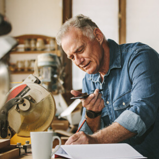 Experienced Woodworker using cell phone to take order in his workshop